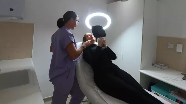 Patient looking in the mirror with Botox practitioner assessing face